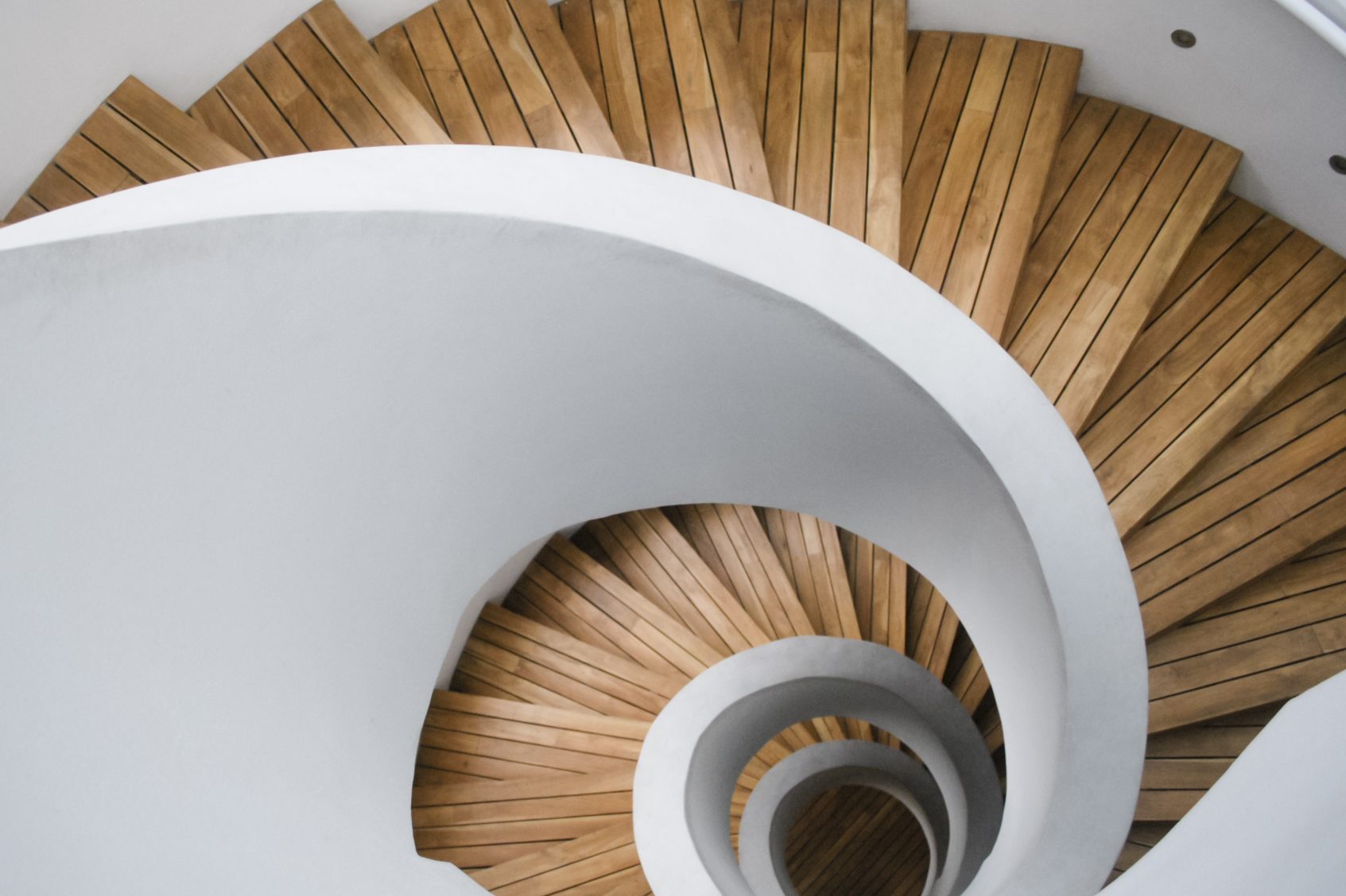 Holztreppe mit spiralförmigem Design, die nach unten führt.